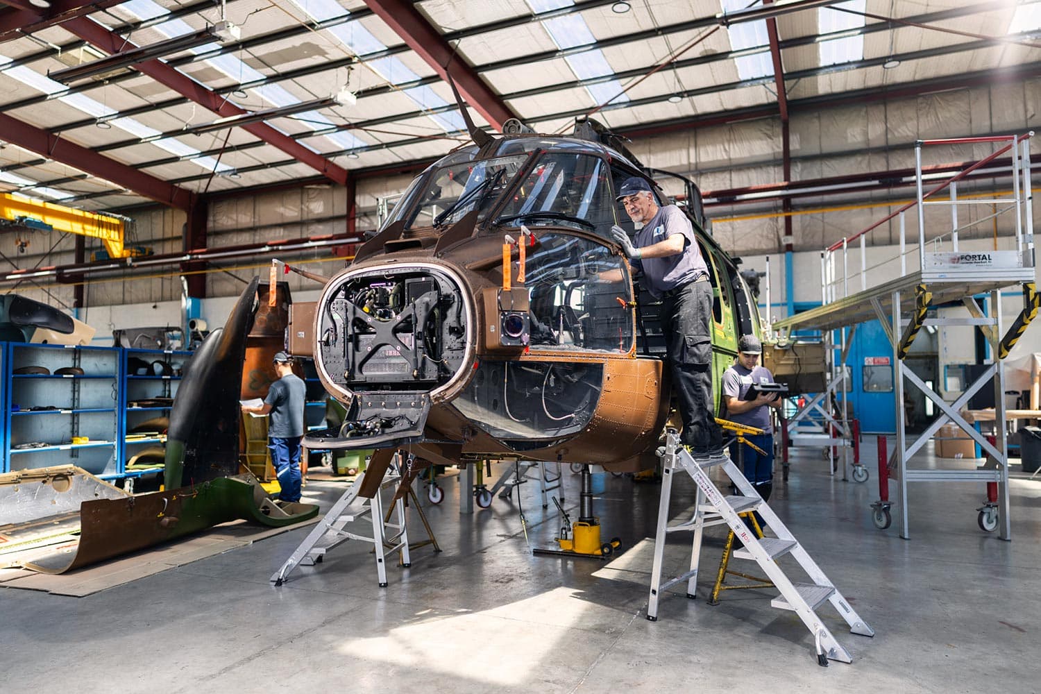 Aeronautical technicians working on a helicopter in a hangar, illustrating team spirit at Sabena technics