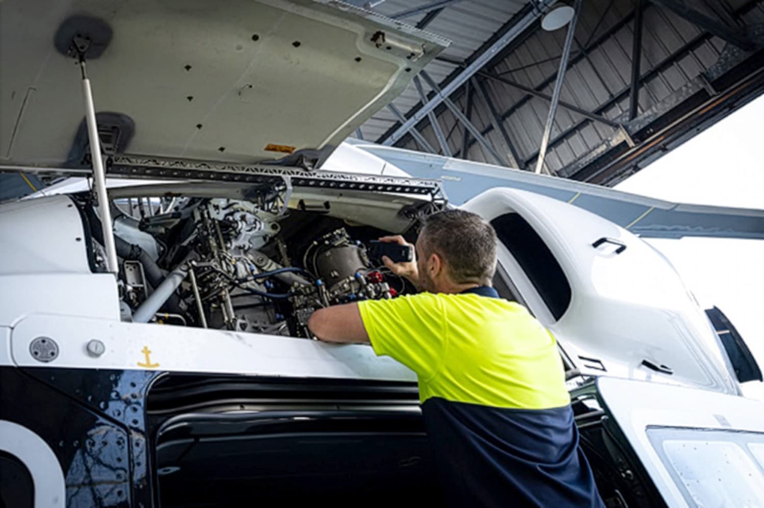 Sabena technics technician carrying out maintenance on a helicopter engine inside a hangar