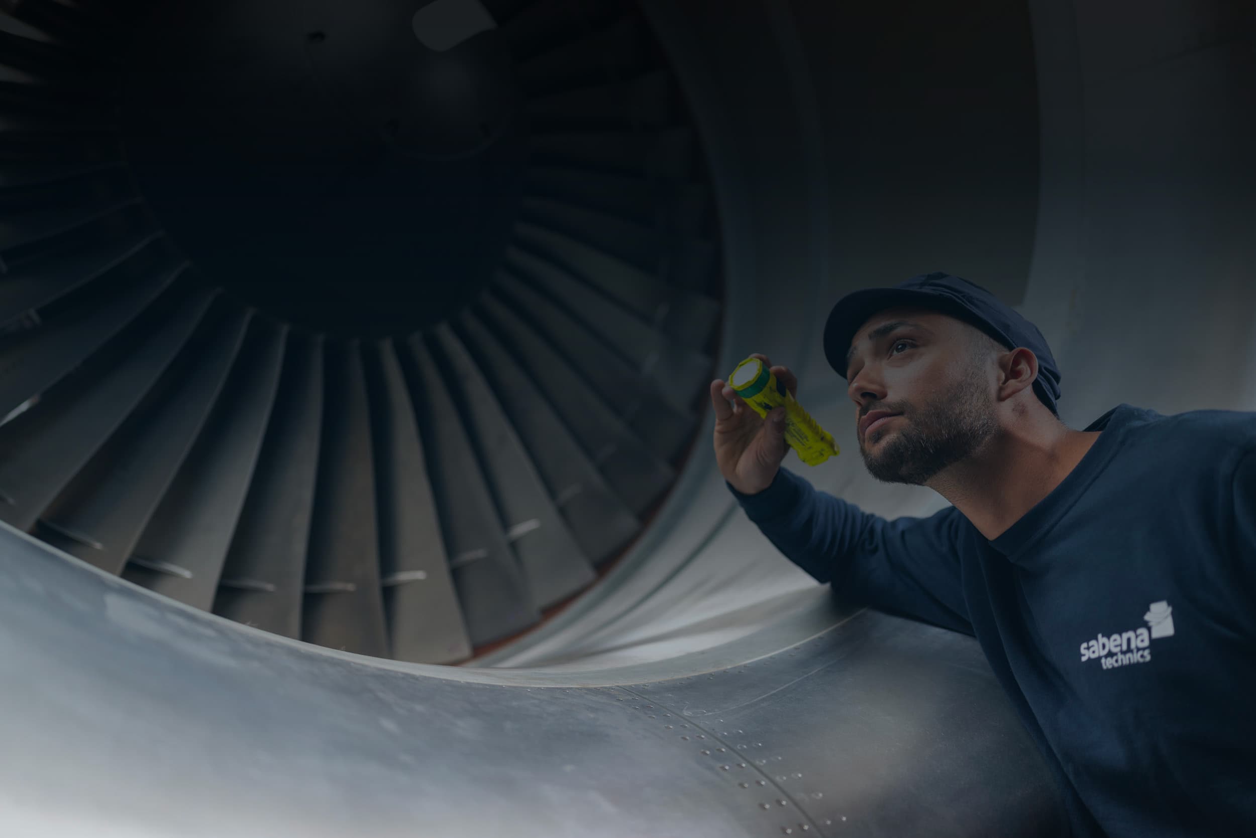 Sabena technics technician inspecting a jet engine turbine using a flashlight