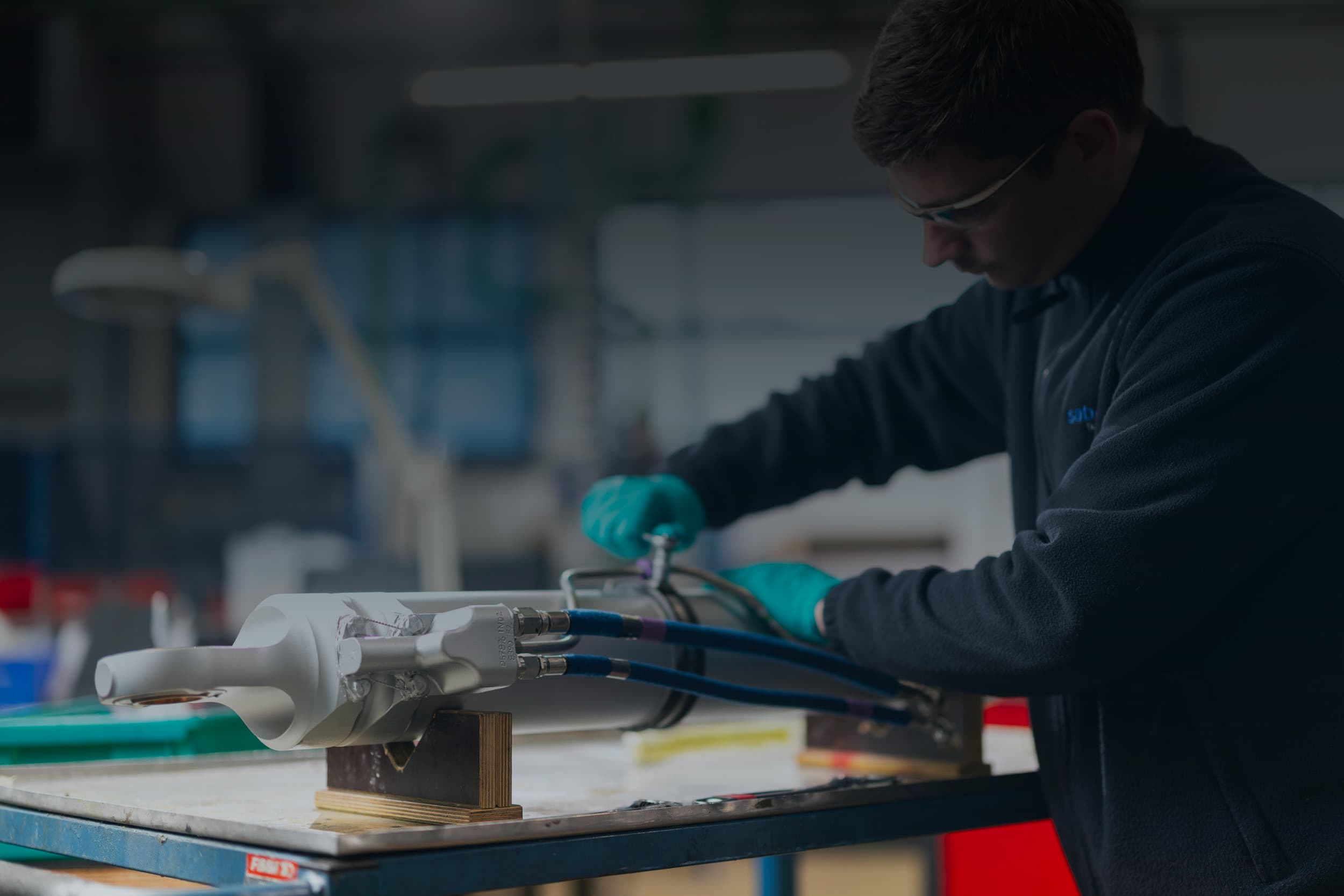 Mécanicien Sabena technics travaillant sur un composant hydraulique en atelier