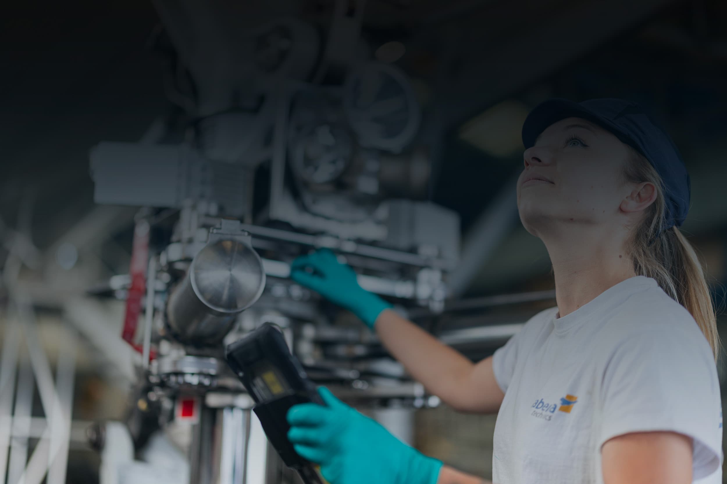 Sabena technics female aeronautical technician inspecting a mechanical component with a control device